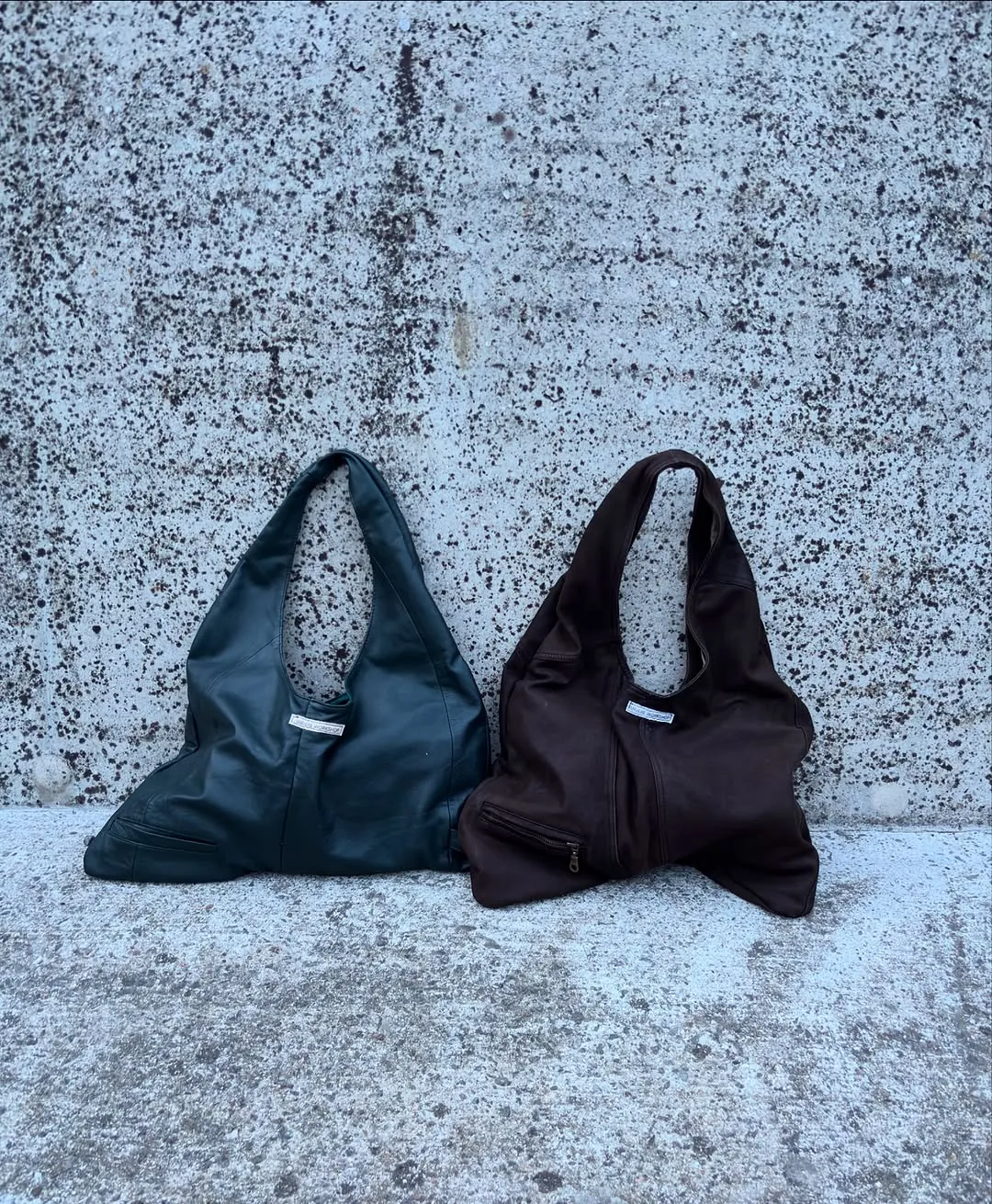 Two shopper bags hanging against a concrete wall